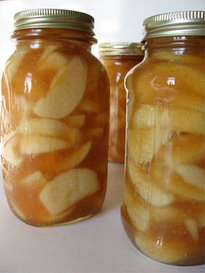 Three staggered mason jars. Each jar is filled with apple pie filling.